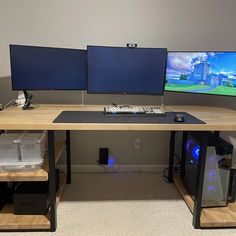 two computer monitors sitting on top of a wooden desk