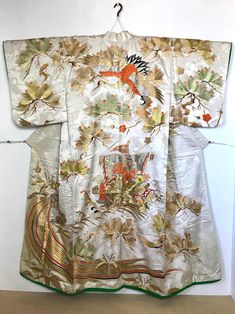 An embroidered Uchikake vintage wedding Kimono. Fits size S-M. Sash sold separately. Crane bird, flying Turtle, Pine branches & Treasure Ship Embroidery.   This Japanese gown is heavy weight with extensive embroidery.  Shorter sleeve length for a sophisticated lady.  Please read full description. Fits a USA size S-M. *$100 Express Shipping has been included in price & is Non-refundable.  Please review photos and description carefully before ordering. Thank you! MATERIAL:  Heavily embroidered silk  fabric.  Interior synthetic with padded bottom. COLOR:  Ivory white with metallic silver bright orange green yellow & embroidery in metallic gold. DETAILS:  Fabric has crane pattern tone-on-tone with silver metallic sparkles and extensive gold embroidery. CONDITION:  Used, vintage.  Light stain o Flying Turtle, Crane Flying, Ship Embroidery, Japanese Wedding Dress, Treasure Ship, Crane Pattern, Yellow Embroidery, Japanese Wedding, Wedding Kimono