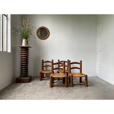 four wooden chairs sitting in front of a mirror and vase with flowers on top of it