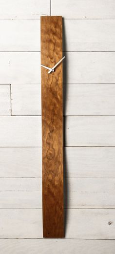 a clock made out of wood on the wall next to a white wooden planked wall