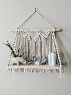 a macrame hanging on the wall with some plants and other things in it