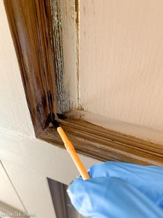 a person with a blue glove and an orange stick sticking out of the corner of a door