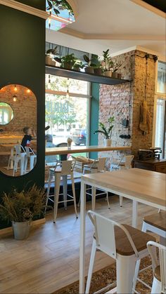 the interior of a restaurant with tables, chairs and potted plants on the wall