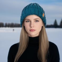 a woman wearing a blue knitted hat in the middle of a snow covered field