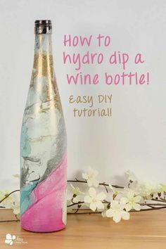 a bottle that is sitting on top of a table with flowers in front of it and the words how to hydro dip a wine bottle