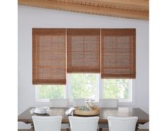 a dining room table with four chairs and bamboo blinds