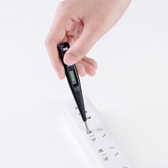 a person is using a digital thermometer to check their temperature on a white surface