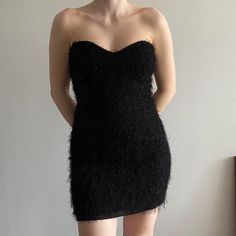 a woman in a short black dress is posing for the camera with her hands on her hips