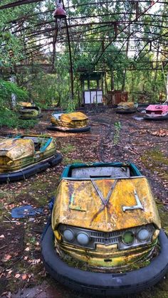 an abandoned car sits in the middle of a forest filled with trees and other junk