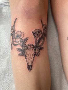 a couple of tattoos on the legs of someone's legs, one with a deer skull and flowers