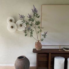 a vase with some flowers in it sitting on a table next to a mirror and two stools