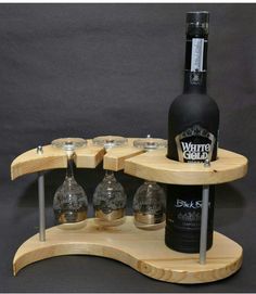 a wine bottle and four glasses on a wooden shelf with metal legs for the bottom