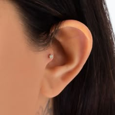 a woman's ear is shown with a single diamond in the middle and behind it