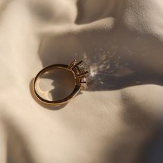 a gold ring sitting on top of a white sheet with the sun shining through it