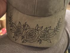 a baseball cap with roses embroidered on the front and side, sitting in someone's hand