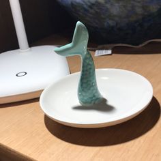 a ceramic figurine sitting on top of a white plate next to a computer mouse