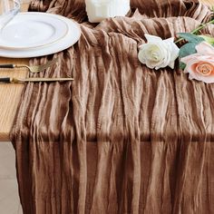 the table is set with white and pink flowers, silverware, and napkins