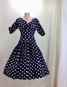 1950's Navy Blue & Creamy White Polka-Dot Drop-Waist Dress. Quality cotton fabric with a fitted bodice and a drop waist, a full gathered skirt, and a neckline that V'S in the front as well as the back. The drop waist is 3 inches lower on the sides than in the front.. which adds interest and wow factor to the silhouette. Such a beautiful dress!! There is a metal zipper that runs down the back of this dress for that perfect tailored hourglass fit. This garment is in EXCELLENT VINTAGE CONDITION Vintage Dress With Full Skirt And Fitted Top, Vintage Fitted Dress With Full Skirt, Fitted Polka Dot Vintage Dress, Fitted Full Skirt Vintage Dress For Vintage Fashion, Retro Dress With Lined Fitted Waist, Fitted Vintage Dress With Full Skirt For Vintage Fashion, Fitted Full Skirt Vintage Dress, Retro Fitted Dress With Full Skirt, Fitted 1950s Polka Dot Dresses