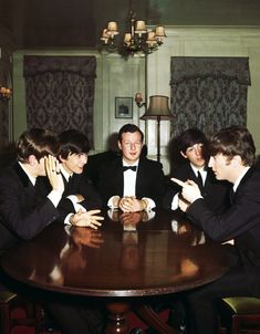 four men in suits sitting around a table