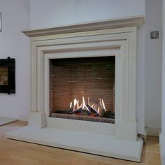 a fire place in the middle of a room with wood flooring and white walls