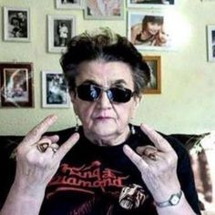 an older woman wearing sunglasses making the peace sign with her hands while sitting on a couch