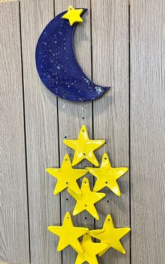 three yellow stars hanging from the side of a wooden wall next to a blue moon