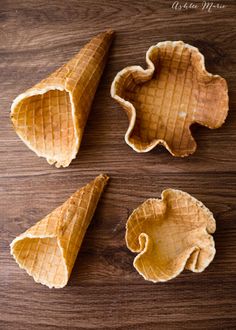 three waffle cones on a wooden surface with one cut in half and the other empty