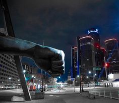 a large hand is on the back of a bench in front of a cityscape