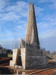 a very tall stone structure sitting on top of a dirt field next to a train track