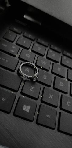 a ring is sitting on the keyboard of a laptop computer that has been placed on it