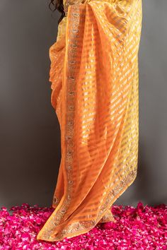 Yellow and orange saree with an ombre woven stripe base highlighted by zardozi embroidery. Comes with matching embroidered blouse.
Components: 2
Pattern: Embroidered
Type Of Work: Zardozi, Gotapatti
Neckline: Round
Sleeve Type: Half
Fabric: Tissue
Color: Orange,Yellow
Other Details: 
Woven zari stripes
Placed embroidery
Occasion: Mehendi and Haldi,Sangeet - Aza Fashions Orange Pre-draped Saree For Diwali, Festive Orange Georgette Blouse Piece, Traditional Orange Pre-draped Saree With Zari Weaving, Orange Georgette Blouse Piece For Festive Occasions, Orange Pre-draped Saree With Zari Work, Traditional Orange Georgette Pre-draped Saree, Navratri Orange Blouse Piece, Orange Georgette Blouse Piece For Navratri, Traditional Orange Georgette Blouse Piece