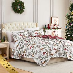 a bed covered in christmas themed comforters next to a christmas tree