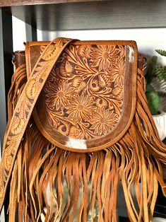 9" H x 10" W x 5" D Western style bag with cowhide and leather adorned with leather fringe Flap snaps closed and has zipper closure at top zipper and open pocket inside tooled leather strap - 48” crossbody (removable Select cowhide pattern option from drop down menu. Cowhide and leather colors vary. Select exact item from drop down. Not customizable - handmade by American Darling Products Cowhide Pattern, Nashville Outfit, Fringe Handbags, Leather Colors, Tan Handbags, Nashville Outfits, Fringe Purse, Leather Saddle Bags, Tooled Leather