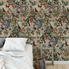 a bed sitting next to a wall covered in lots of different types of flowers and leaves