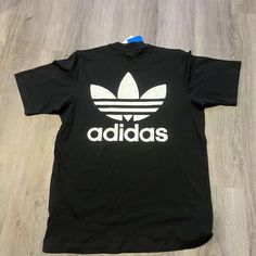 Brand New With Tags, Size M Black Sporty Shirt With Relaxed Fit, Black Relaxed Fit Sporty Shirt, Adidas Casual Tops For Streetwear, Adidas Casual Streetwear Tops, Casual Black Shirt With Letter Print, Adidas Cotton Shirt For Streetwear, Classic Black Top With Graphic Print, Black Crew Neck Shirt For Spring, Adidas Black Crew Neck Shirt