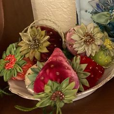 a bowl filled with fruit and flowers on top of a table