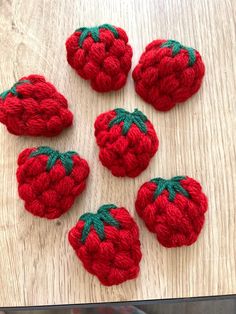 four crocheted strawberries sitting on top of a wooden table next to each other