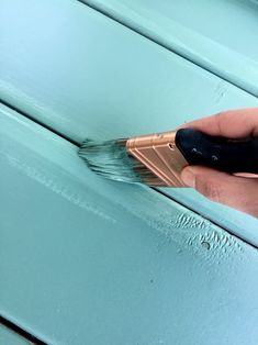 a person is using a brush to paint the side of a blue painted wooden door