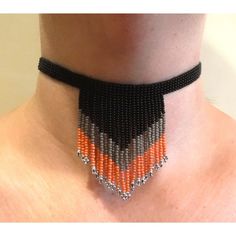 an orange and black beaded choker on a woman's neck with silver beads