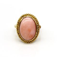 -  Presented is a lovely 18 karat yellow gold and coral ring. This is a relatively  contemporary piece, but the style is reminiscent of antique coral rings, very  elegant. The ring is set with a beautiful oval cabochon of peachy pink coral  inside a ropetwist border. The coral cabochon measures about 15.7 by 11.3  millimeters.  This ring is stamped and guaranteed 18k (750=18k), as well as a maker's mark  of AJF.  This ring is in excellent condition. The coral is well set with no chips.  The ring Elegant Oval Coral Rings, Elegant Coral Oval Rings, Elegant Oval Coral Jewelry, Elegant Coral Oval Jewelry, Coral Elegant Wedding Rings, Elegant Coral Wedding Rings, Coral Oval Jewelry For Weddings, Oval Coral Cabochon Jewelry, Coral Oval Cabochon Jewelry