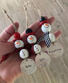 a hand holding four snowmen ornament ornaments with name tags on each one