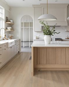 a large kitchen with white cabinets and wooden flooring, along with an island in the middle