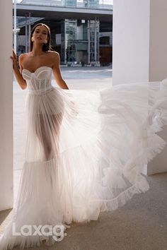 a woman in a white dress is standing by a pillar and looking off to the side