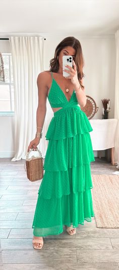 a woman in a green dress taking a selfie with her cell phone and holding a wicker basket