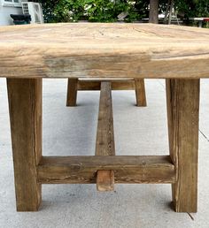 a wooden table sitting on top of a cement floor next to a green planter