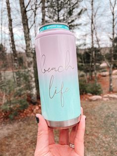 a person holding up a pink and blue can with the words beach life written on it