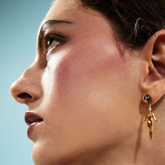 a close up of a woman's face with earrings on her ear and nose