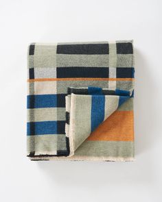 a plaid blanket folded on top of a white table with an orange and blue stripe