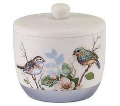 two birds sitting on top of a flower covered jar