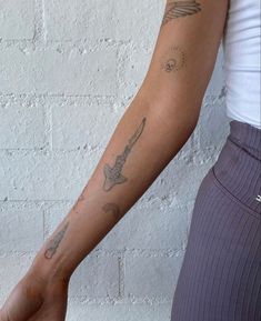 a woman's arm with tattoos on it and a brick wall in the background